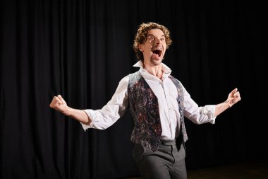 Yelekli ve kravatlı bir adam güçlü bir çığlıkla yoğun duyguları ifade eder..