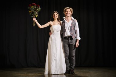 A handsome man and a beautiful woman pose on stage during theater rehearsals. clipart