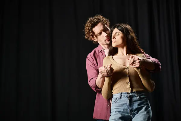 stock image A man and a woman stand poised in front of a dark backdrop.