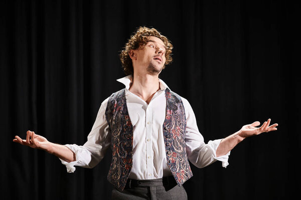 Стильный мужчина в белой рубашке и жилете позирует перед черным занавесом.