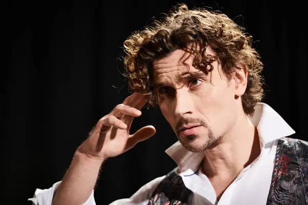 stock image A man with curly hair holds his hand up to his ear, listening attentively.