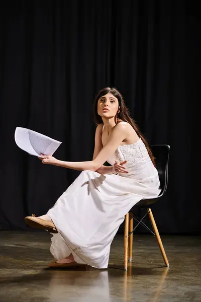 stock image A woman in a white dress seated on a chair.
