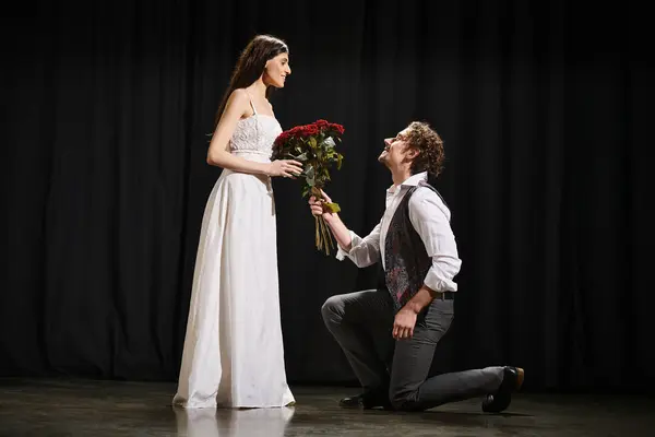 Mężczyzna Klęczy Obok Kobiety Trzymającej Kwiaty Podczas Próby Teatralnej — Zdjęcie stockowe