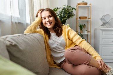 Orta yaşlı bir kadın oturmuş, kameraya gülümsüyor..