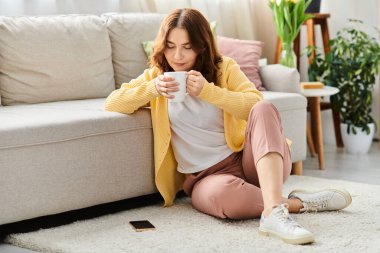 Orta yaşlı bir kadın oturmuş, elinde bir fincan kahve tutuyor..