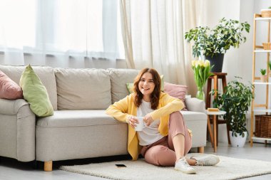 Orta yaşlı bir kadın zarif bir şekilde koltuğun önünde oturuyor..