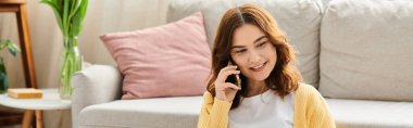 Kanepede oturan orta yaşlı bir kadın, bir telefon konuşmasına dalmış..