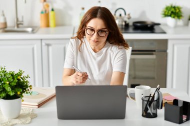 A middle-aged woman engrossed in work on her laptop at a cozy table. clipart