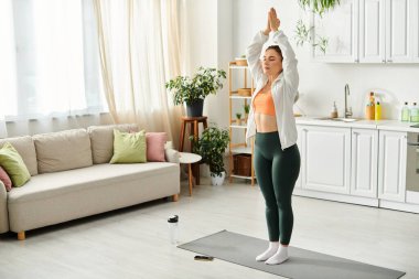 Orta yaşlı kadın rahat oturma odasında yoga yapıyor..