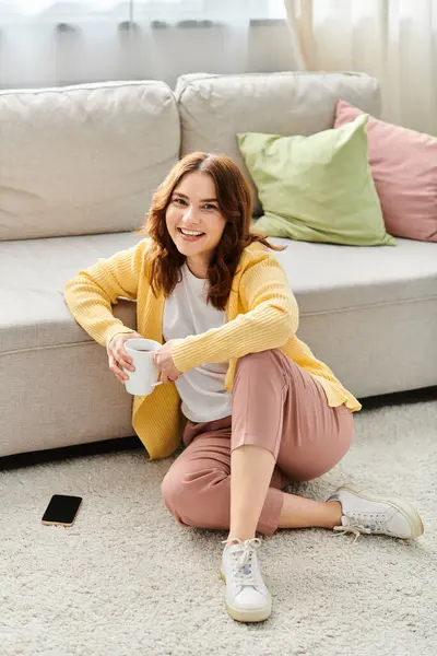 stock image Middle-aged woman sitting peacefully on floor with coffee in hand.