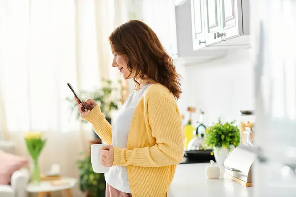 Middle Aged Woman Engrossed Cell Phone Kitchen — Stock Photo, Image