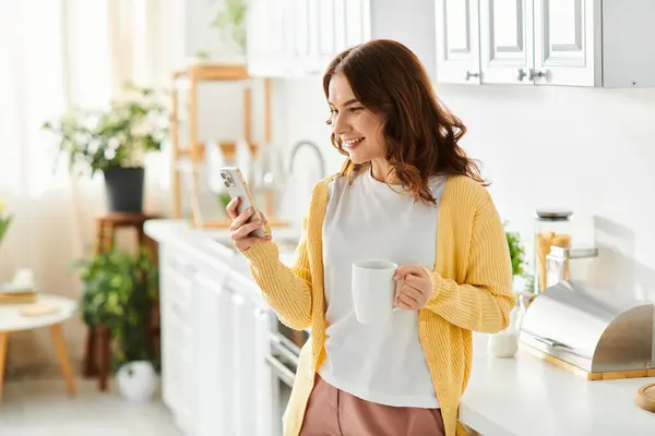 Middle Aged Woman Stands Kitchen Engrossed Cell Phone — Stock Photo, Image
