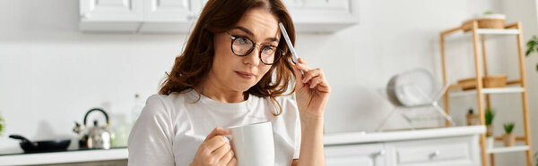 A beautiful middle-aged woman sipping coffee in a cozy kitchen setting.