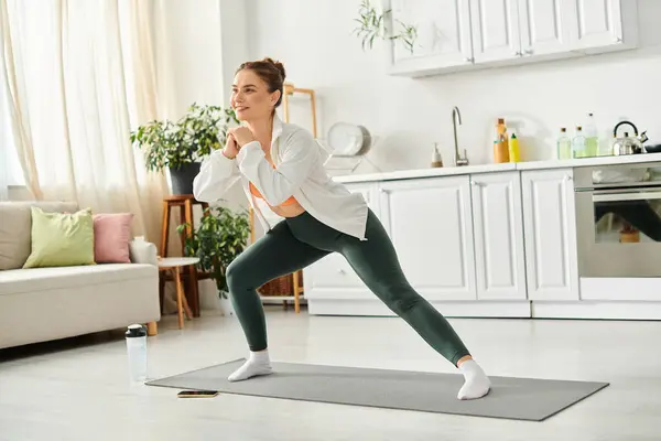 stock image Middle-aged woman gracefully performs a yoga pose in her cozy living room.