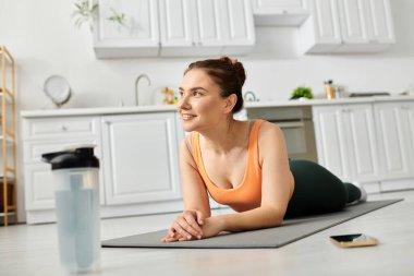 Orta yaşlı bir kadın, rahat bir mutfakta yoga minderinin üzerinde huzur içinde yatıyor..