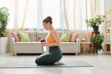 Orta yaşlı bir kadın, rahat bir oturma odasında yoga minderinde huzur içinde meditasyon yapıyor..