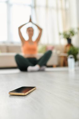 Orta yaşlı bir kadın akıllı telefonun önünde bacak bacak üstüne atmış oturuyor..