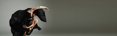 Genç, güzel bir balerin zarif siyah bir elbiseyle dans eder..