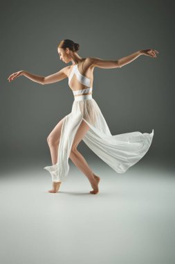 Genç ve güzel bir balerin enerjik bir şekilde beyaz bir elbiseyle dans ediyor..