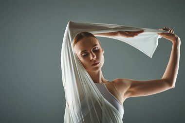 A young ballerina gracefully dances in a white dress with a veil. clipart