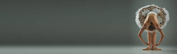 Молодая балерина изящно наклоняется, с ангельскими крыльями на голове..