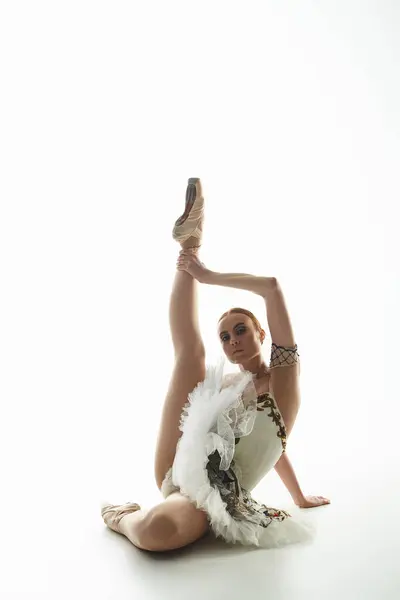 一位身穿白衣的年轻漂亮的芭蕾舞演员优雅地坐着 — 图库照片