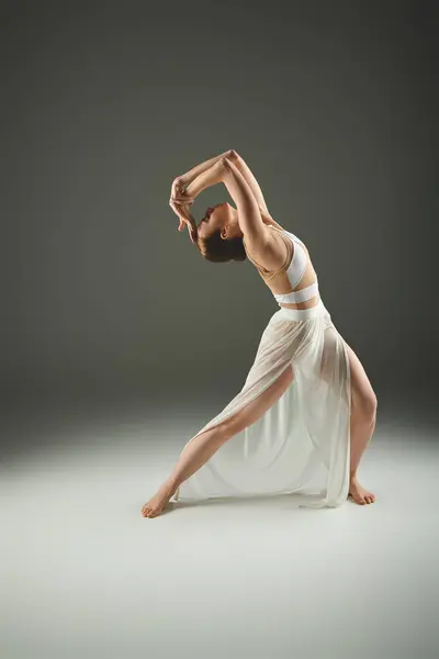 stock image A young woman in a white dress practices a graceful ballet pose.