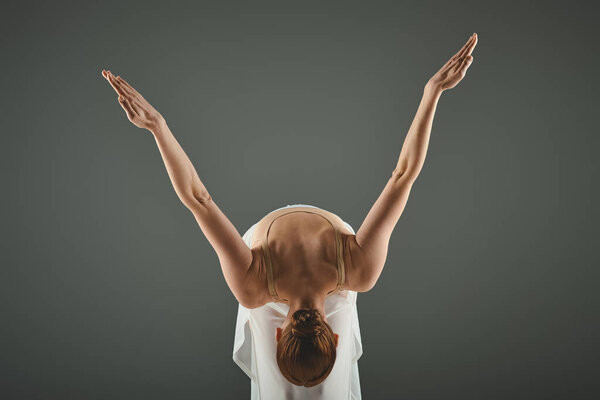 A young, beautiful ballerina with her hands raised elegantly in the air.
