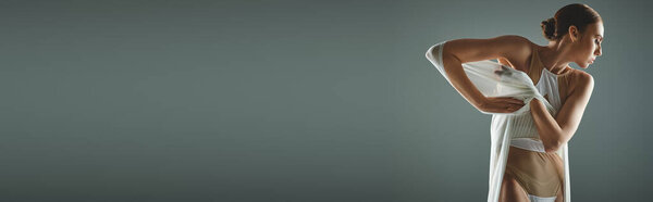 Женщина в белой вуали грациозно стоит в комнате.