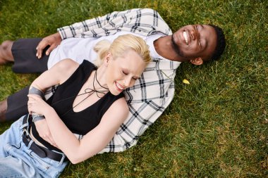 Çok kültürlü bir çift, Afro-Amerikalı bir adam ve beyaz bir kadın, parkta çimlerin üzerinde yatıyorlar..