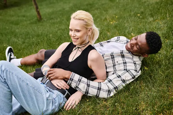 A multicultural couple, an African American man and a Caucasian woman, enjoy a peaceful moment together on the grass.