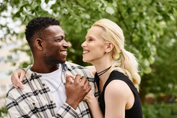 stock image A joyful moment captured as a multicultural couple share genuine smiles in a park.