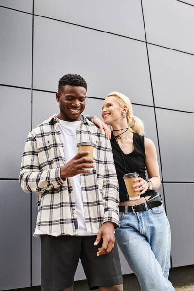 A happy, diverse couple - a man and a woman - standing next to each other in an urban street, sharing a loving embrace.