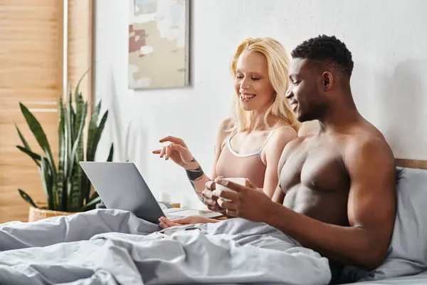 男と女 多文化ボーイフレンドとガールフレンド 快適にベッドに座って ラップトップスクリーンに集中 — ストック写真