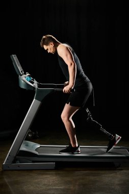 Protez bacaklı bir adam spor salonundaki koşu bandında koşar. Engelleri aşmada kararlılık ve güç gösterir..