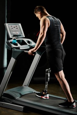 Protez bacaklı engelli bir adam spor salonunda koşu bandında yürüyor..