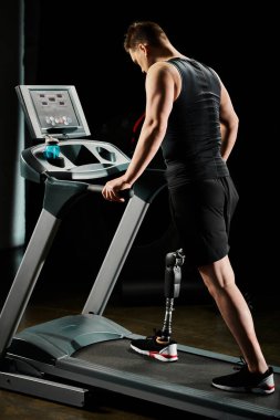 A disabled man with a prosthetic leg walks on a treadmill in a gym. clipart