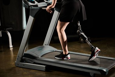 Protez bacaklı kararlı bir adam spor salonundaki koşu bandında koşuyor..