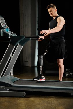 Protez bacaklı bir adam spor salonunda çalışırken koşu bandında durur..