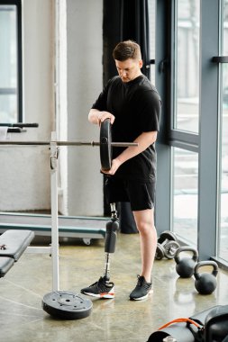 Protez bacaklı engelli bir adam spor salonunda makineyle çalışıyor..