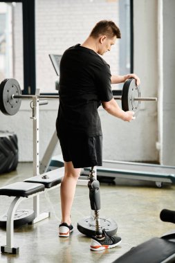 Protez bacaklı bir adam spor salonunda güç kazanmak ve hareket kabiliyetini arttırmak için makine kullanıyor..