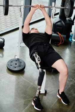 A disabled man with a prosthetic leg wearing a black shirt performs a barbell squat in a gym. clipart