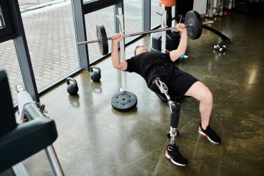 Protez bacaklı bir adam spor salonunda güçlü bir kaldırış yapar. Kararlılık ve güç gösterir..