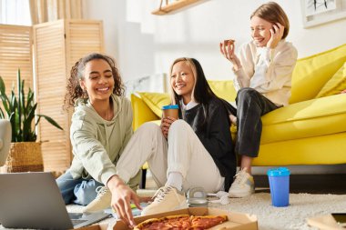 Diverse teenage girls bonding over pizza while seated on the floor in a cozy setting. clipart