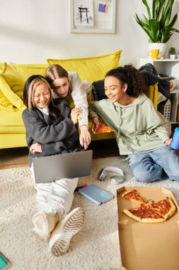 Farklı ırklardan gelen bir grup genç kız yerde toplandı pizzalarını paylaştılar ve birbirlerine eşlik ederek eğlendiler..