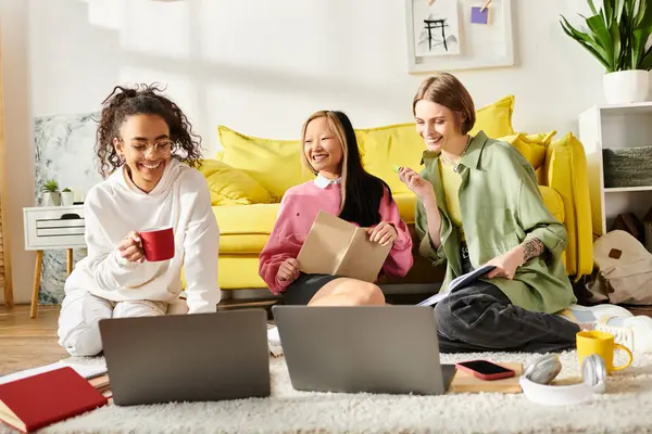 三个不同种族的少女 拿着笔记本电脑坐在地板上 专心致志地学习 并通过教育培养友谊纽带 — 图库照片