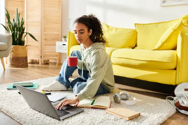 一个坐在地板上的少女专心致志地在家用笔记本电脑学习 — 图库照片