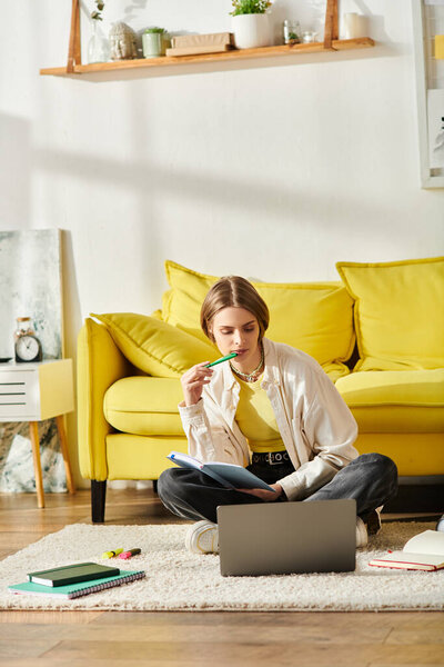 Девочка-подросток, погруженная в электронное обучение, сидит на полу, поглощенная своими ноутбуками.