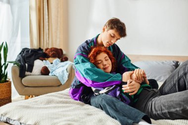 Güzel görünümlü, canlı giyinmiş, neşeli kız arkadaşını evinde kucaklayan neşeli bir adam.