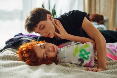 Çekici, şık elbiseli bir çift yatakta birlikte yatarken öpüşmeye hazırlanıyor.